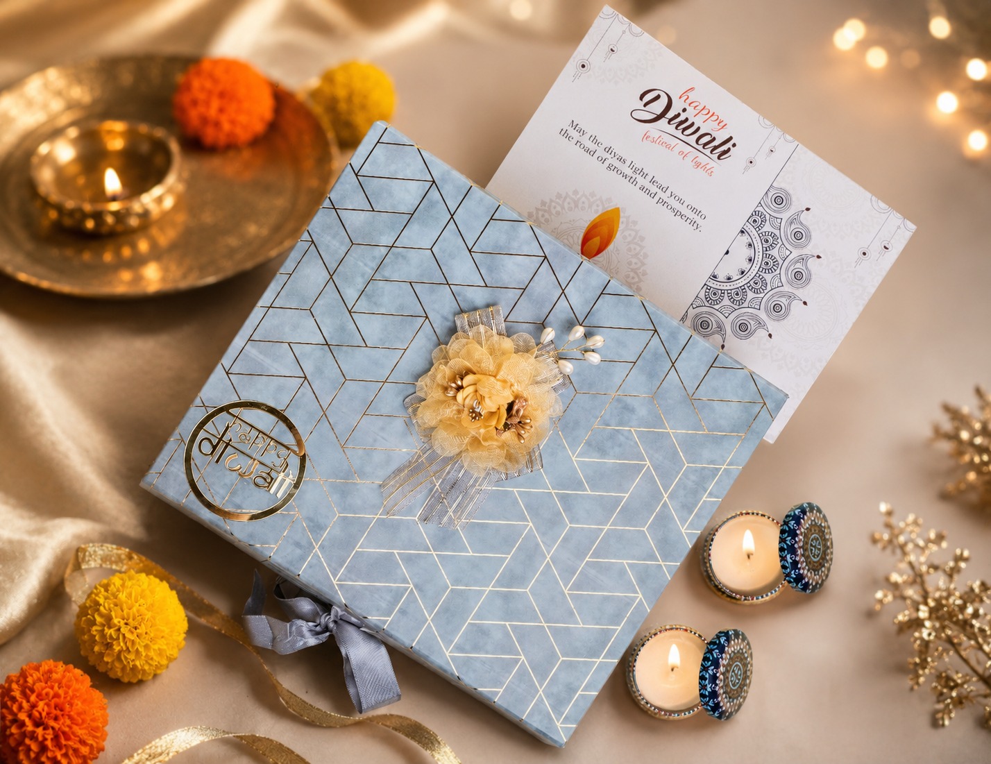 Light blue geometric Happy Diwali gift box with gold flower and decorative diyas