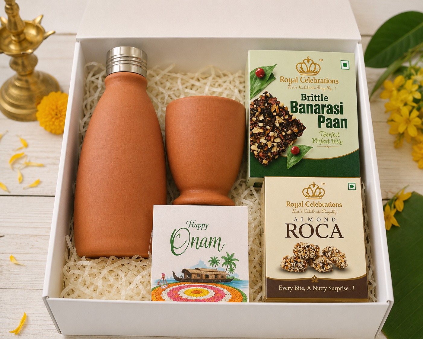 White Happy Onam box hamper with terracotta bottle, cup, Banarasi paan and almond roca